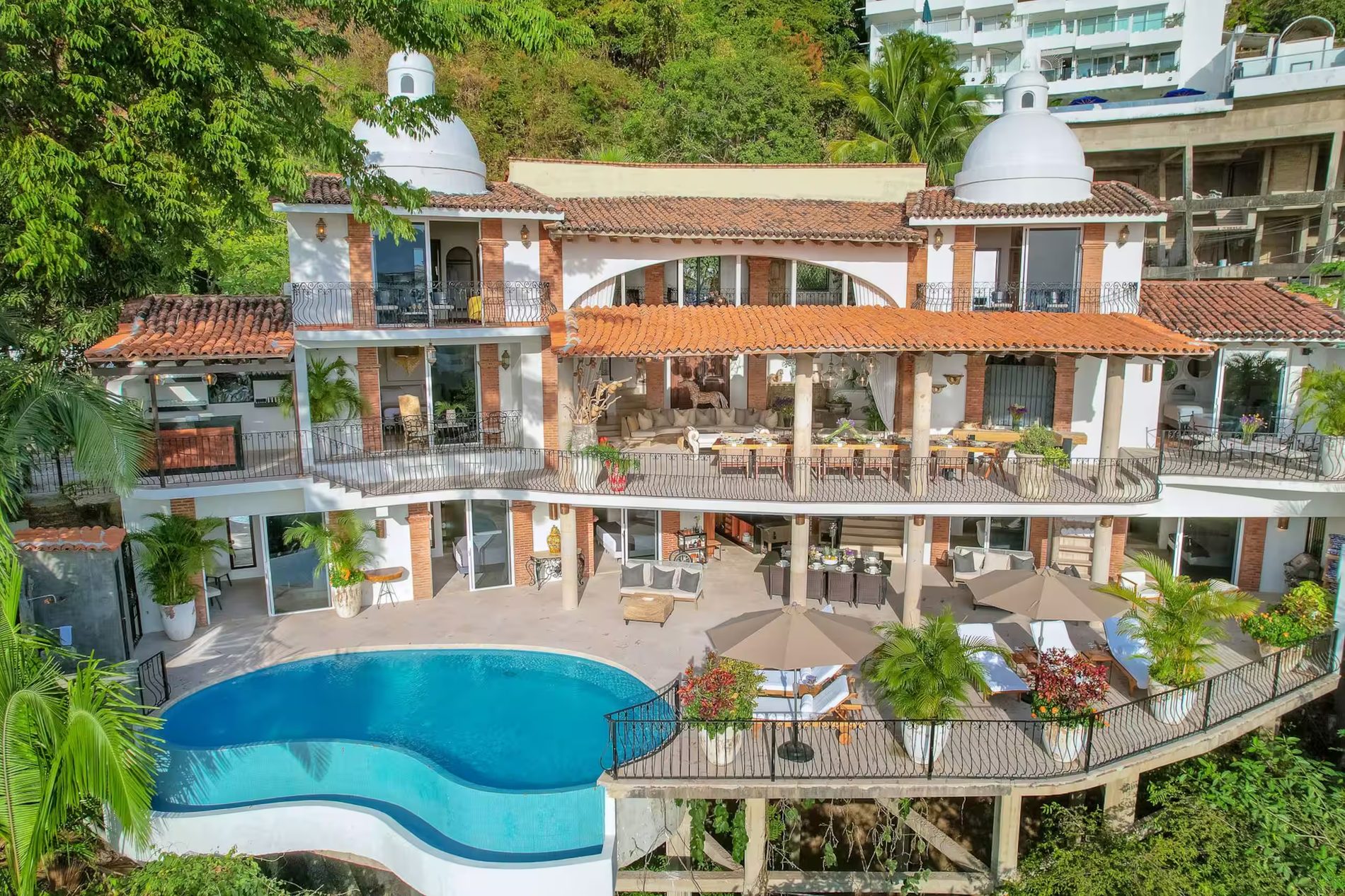 Aerial view of the villa showing three floors of rooms above the pool deck, with each bedroom numbered.